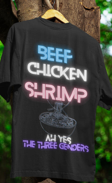 BCS Black Tee a black tee hanging in a tree and on the tee it says, "beef, chicken, shrimp ah yes the three genders." the tone is sily and the colors are the trans flag colors.